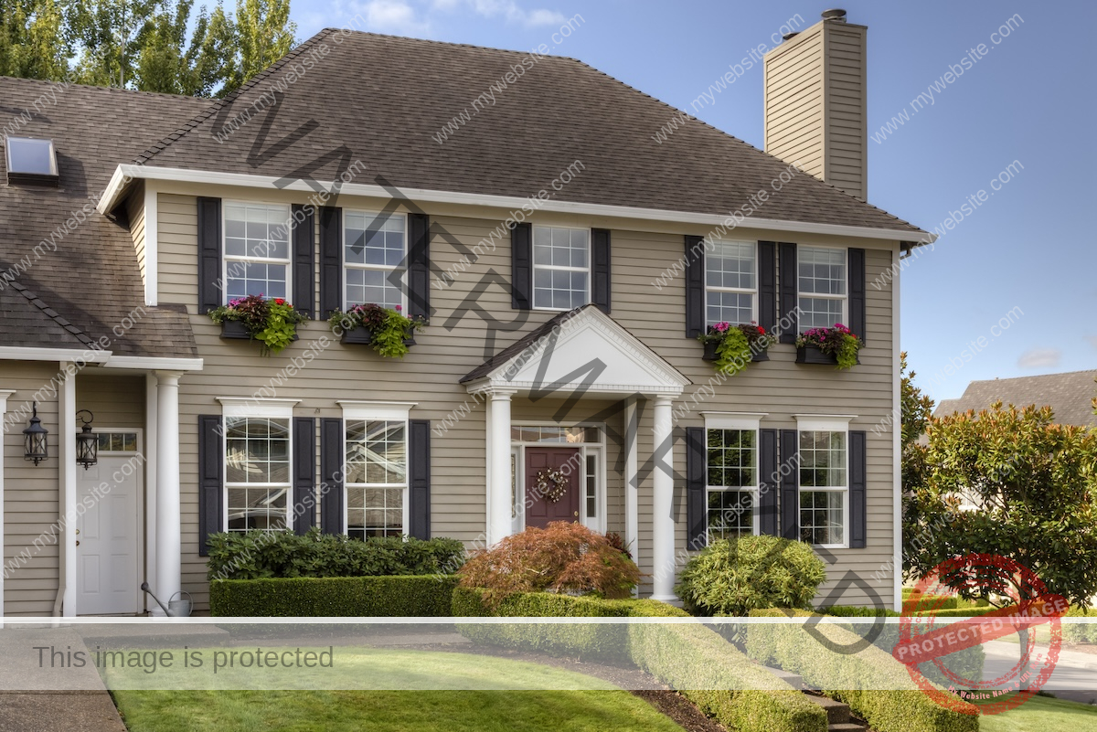 A traditional colonial home with taupe siding and black window features.