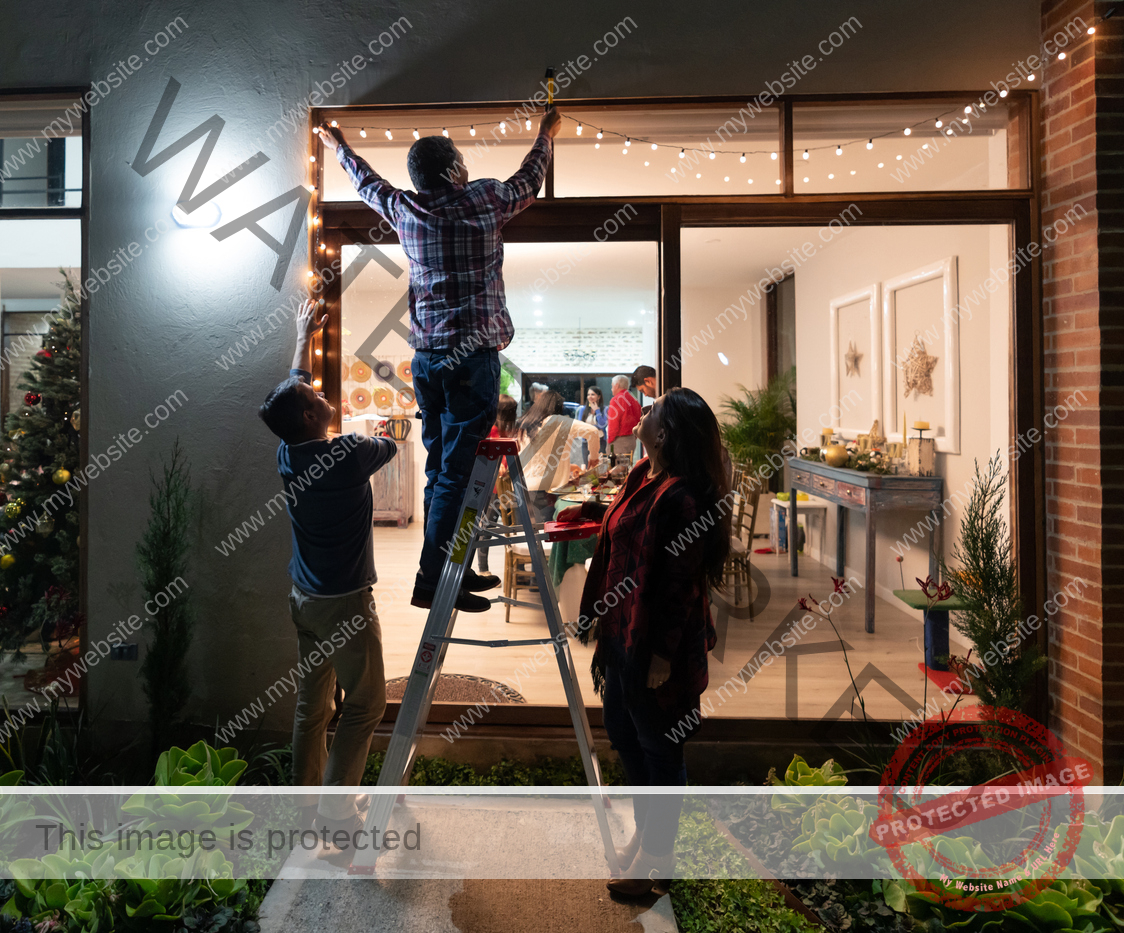 Friends are hanging outdoor string lights on the patio, lighting up the inside of the house.