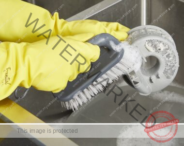 Clean the dishwasher filter with a hand scrub brush wearing yellow rubber gloves.