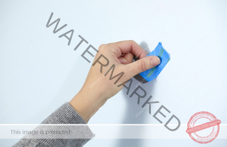 Woman uses painter's tape to mark a spot on the wall.