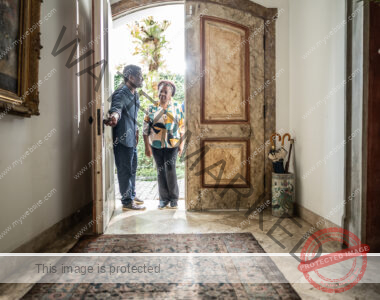 Man and woman entering the lobby of an ornate home.